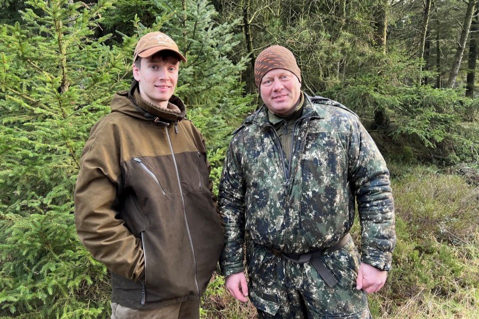 Per står i jagttøj sammen med sin ældste søn ude i skoven.