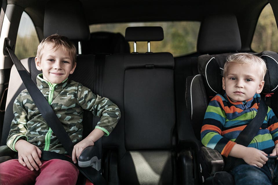 Børn sidder fastspændt på selepuder i bilen