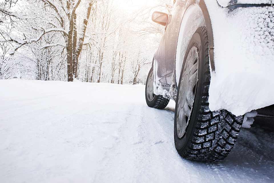 Bil kører med vinterdæk i snevejr
