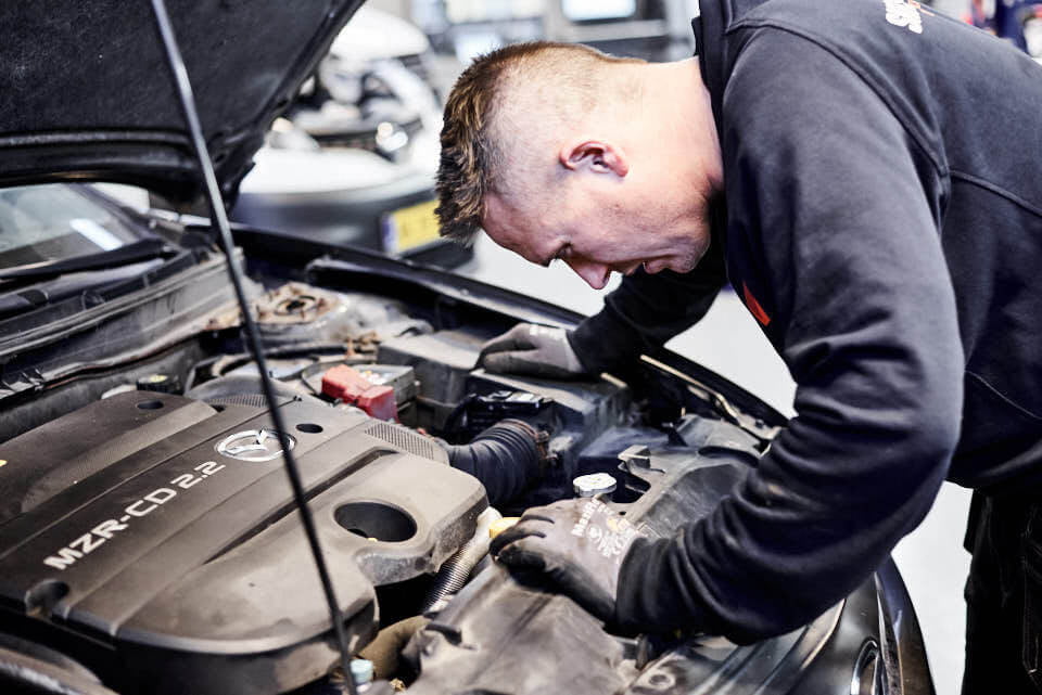 Mekaniker tjekker motorrum på Mazda bil