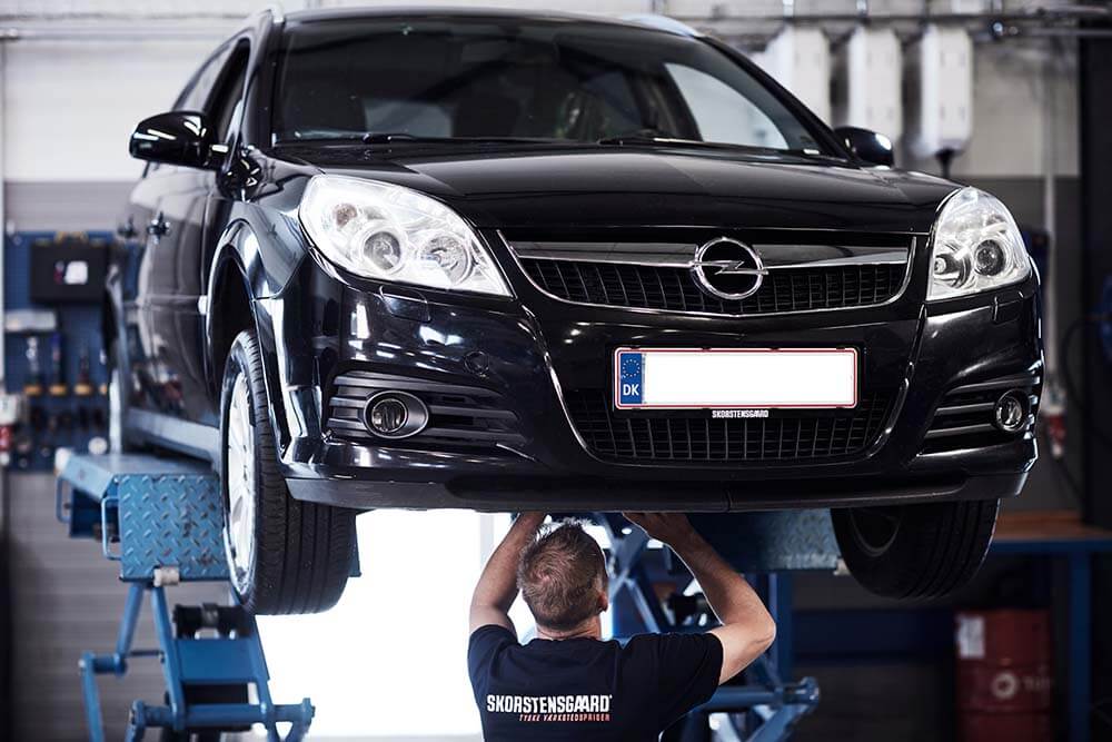 Mekaniker tjekker undervogn på Opel på værksted