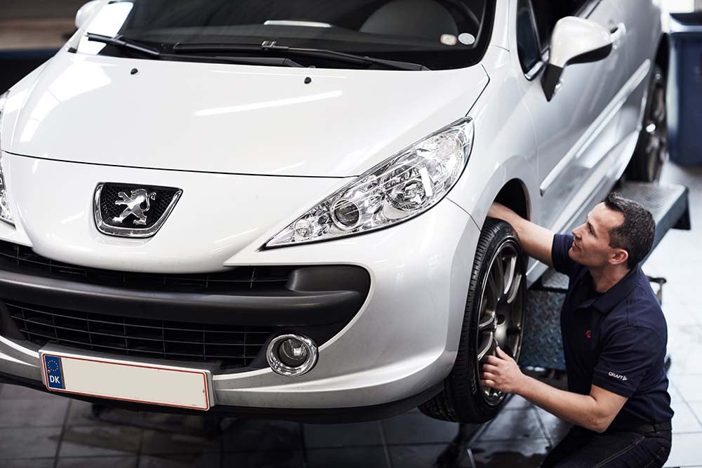 Mekaniker tjekker hjul på Peugeot bil
